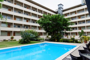 Un hôtel à plusieurs étages, doté d’une piscine et entouré de verdure.