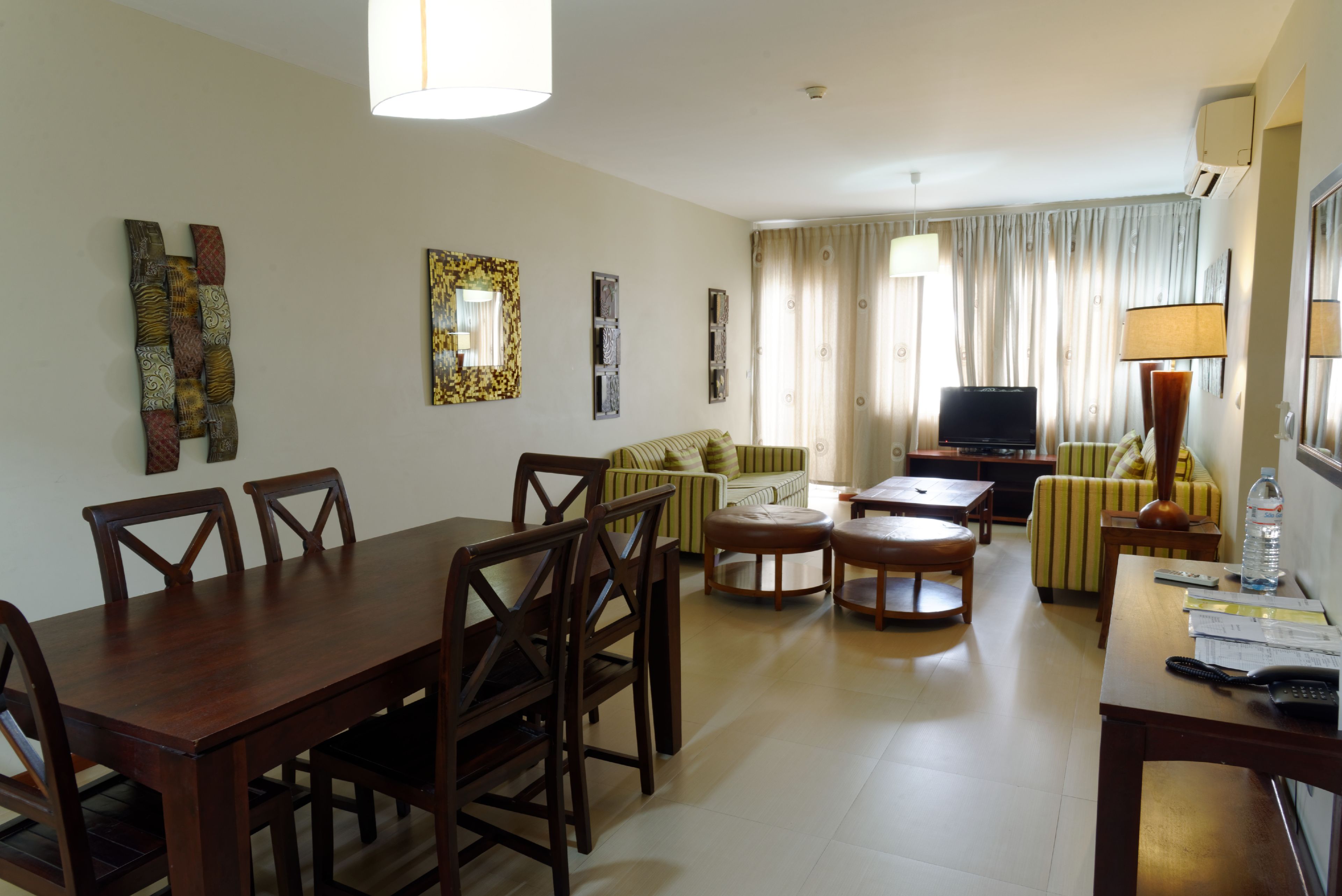 Un comedor con una mesa y sillas de madera, un sofá, un televisor y una lámpara.