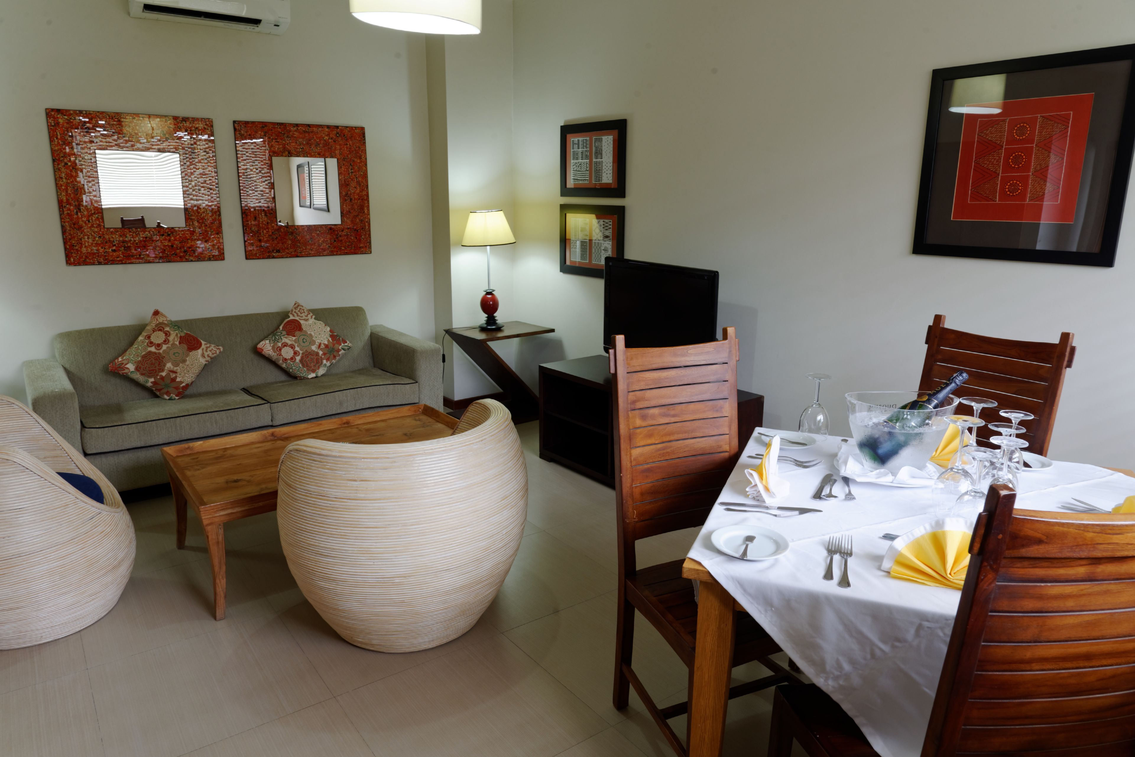 A dining area with a table set for four, a sofa, and two chairs.
