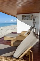 Un salón junto a la playa con mobiliario de mimbre y vistas al océano.