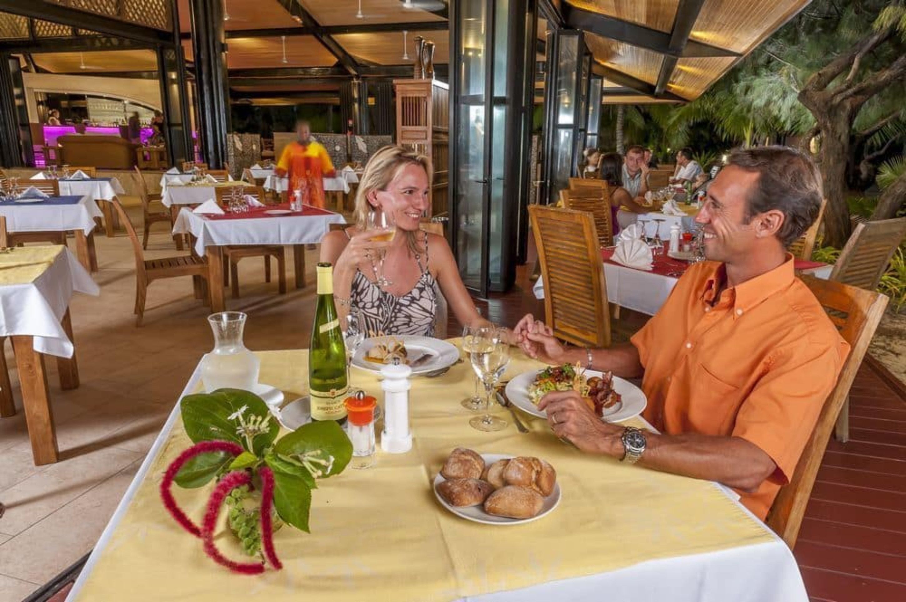 A restaurant with tables set for dining, featuring a variety of dishes and drinks.