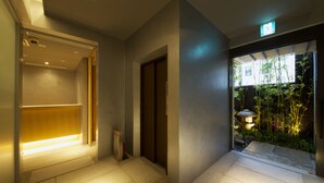 A modern hotel lobby with a reception desk, a private entrance, and a view of a garden. - Aoi Hotel Kyoto (Kyoto)