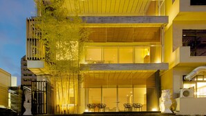 Un edificio de varios pisos con diseño moderno, que cuenta con amplios ventanales y un balcón.