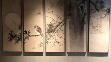 A series of five vertical panels with traditional artwork depicting nature scenes, including birds and trees.