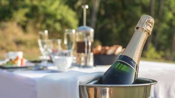 A bottle of champagne in a metal bucket on an outdoor table with a white tablecloth.