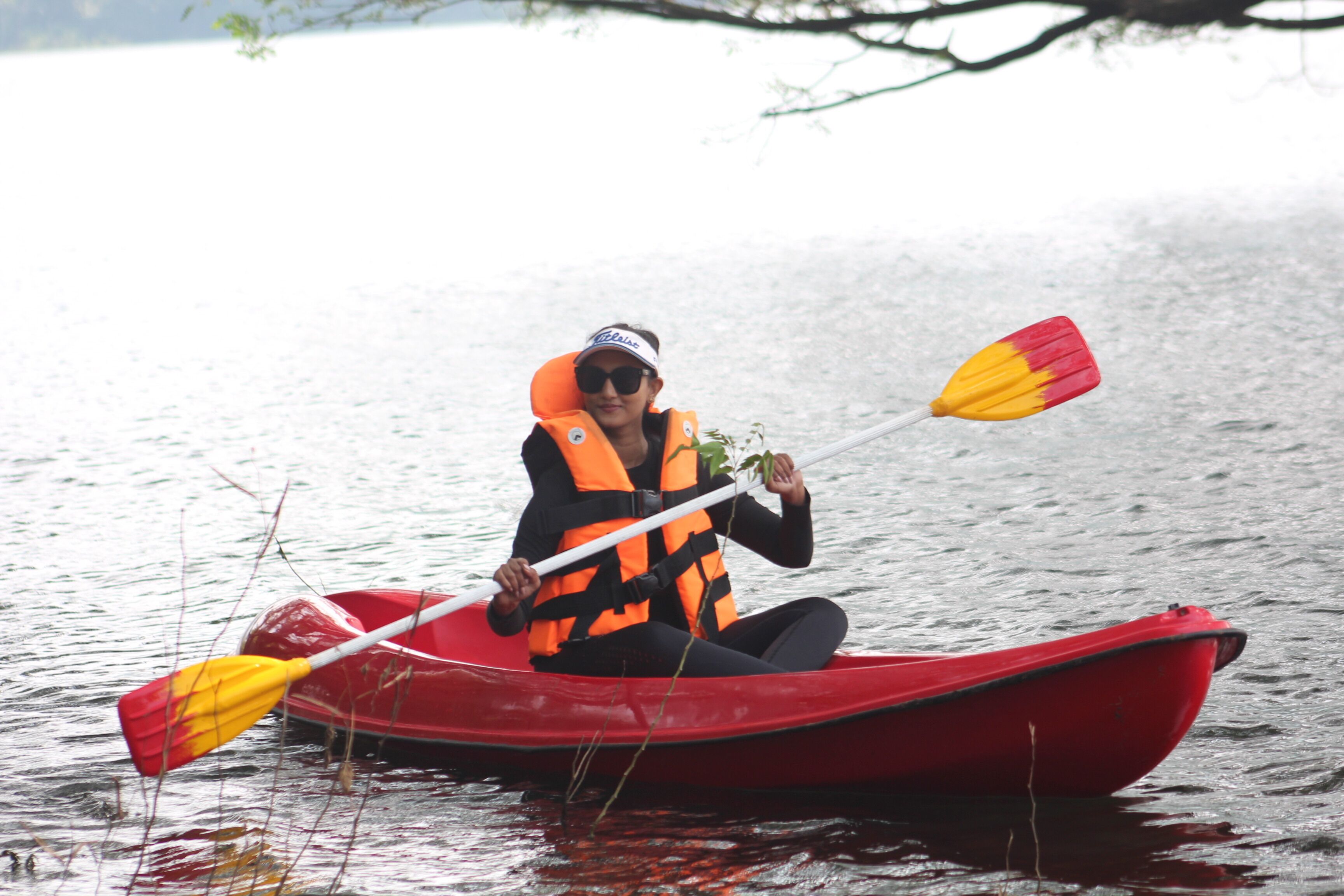 A person in a red kayak on a calm body of water.