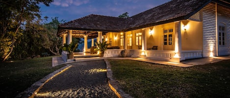 A house with a covered porch, a gravel pathway, and a well-maintained lawn.