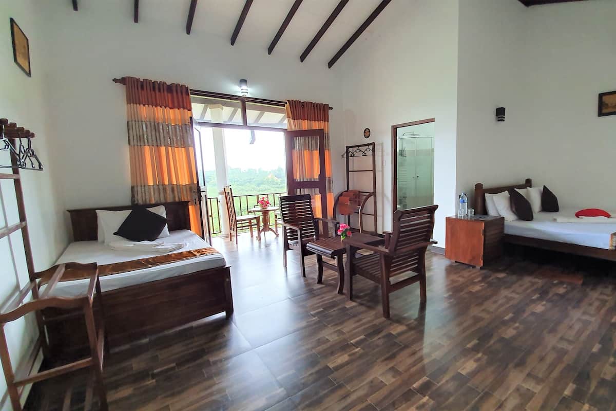 A room with a bed, a sofa, a dining table with chairs, and a balcony with curtains.