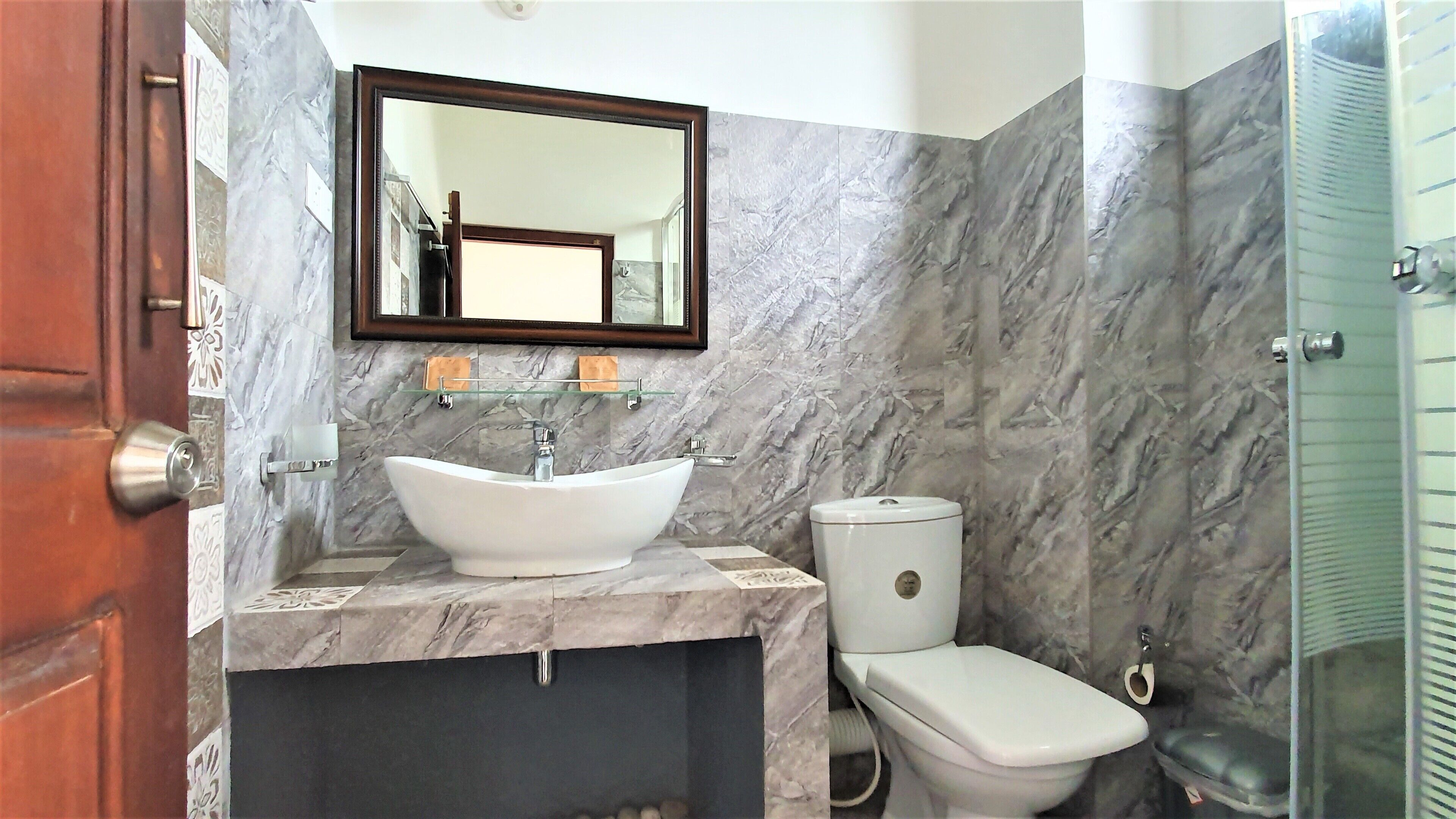 A bathroom with a marble sink, a toilet, and a glass shower enclosure.
