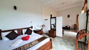 A hotel room with a bed, a wooden nightstand, a vase with flowers, a mirror, and a chair. - Dhammika Magic Palace (Wadduwa)