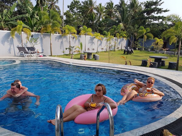 A swimming pool with lounge chairs and palm trees in the background.