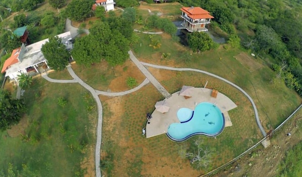 An aerial view of a residential area with a swimming pool, pathways, and houses.