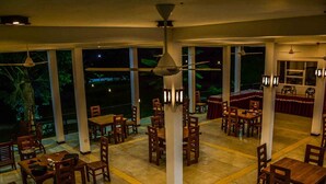 A spacious restaurant with high ceilings and large windows, offering views of the outdoors. - Lake Villa Resort (Weerawila)