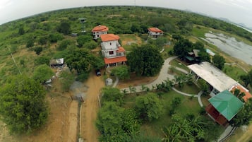 An aerial view of a residential area with multiple houses, a water body, and a watchtower.