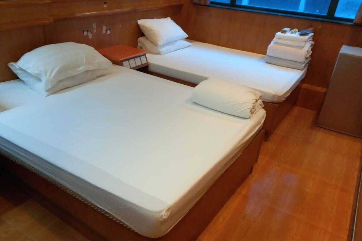 A room with a large bed, two smaller beds, a nightstand, and a small table.