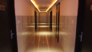 A corridor with a reflective floor, doors on both sides, and a number sign on the left wall. - Hotel Savi Regency (Jaipur)