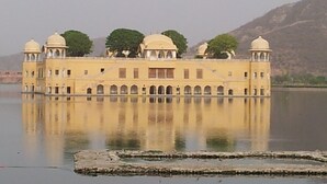 A large, yellow building with multiple domes and arched windows, reflecting in a calm body of water. - Hotel Savi Regency (Jaipur)