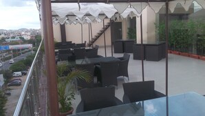 A balcony with outdoor seating, a staircase, and a view of the city. - Hotel Savi Regency (Jaipur)
