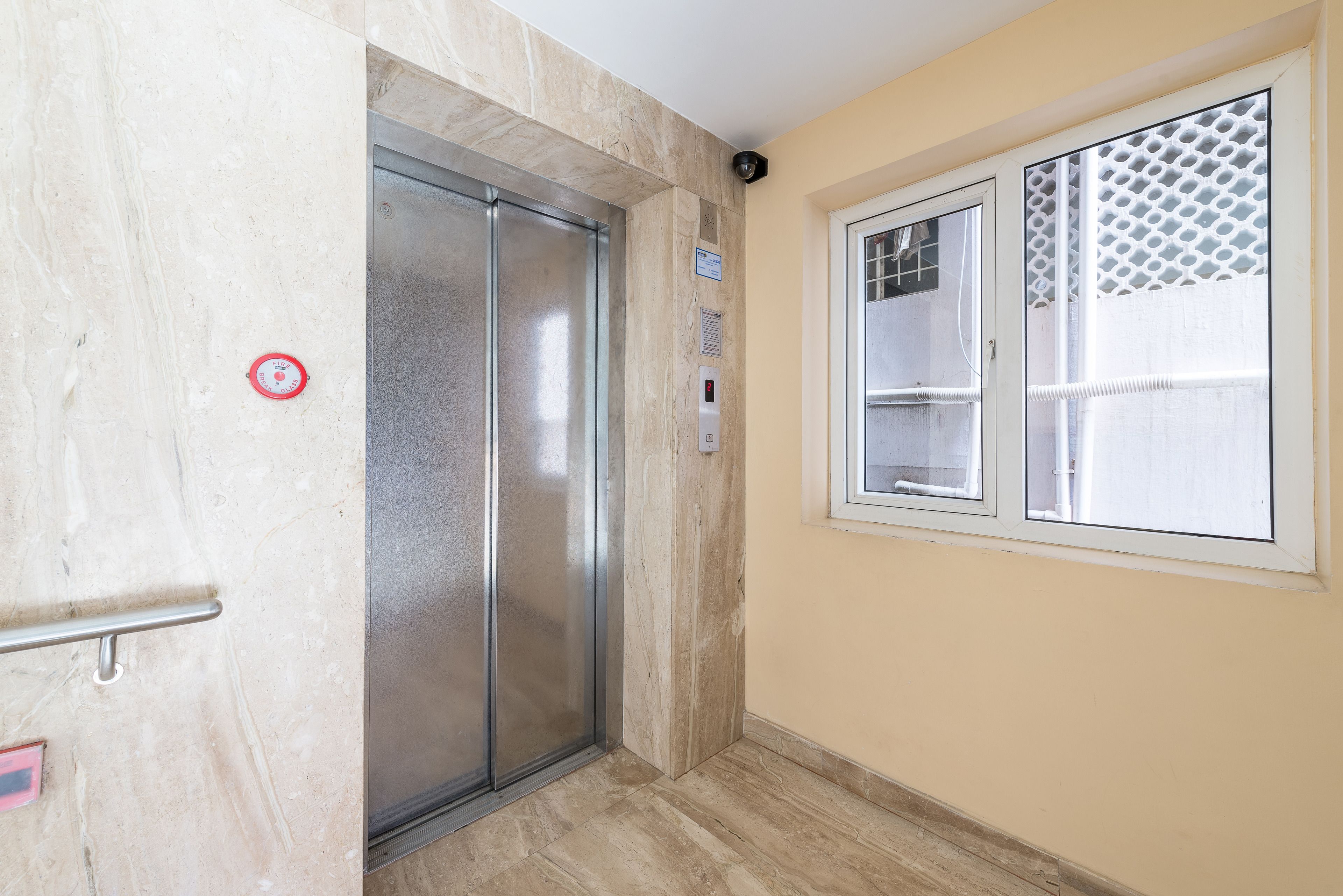 An elevator with a metallic finish, a handrail, and a door with a red circular sign.