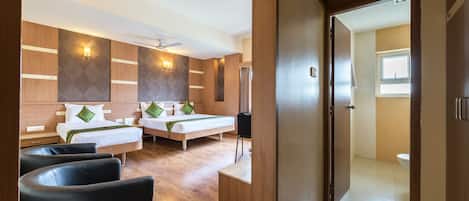 A hotel room with two beds, a seating area, and a view of the bathroom.