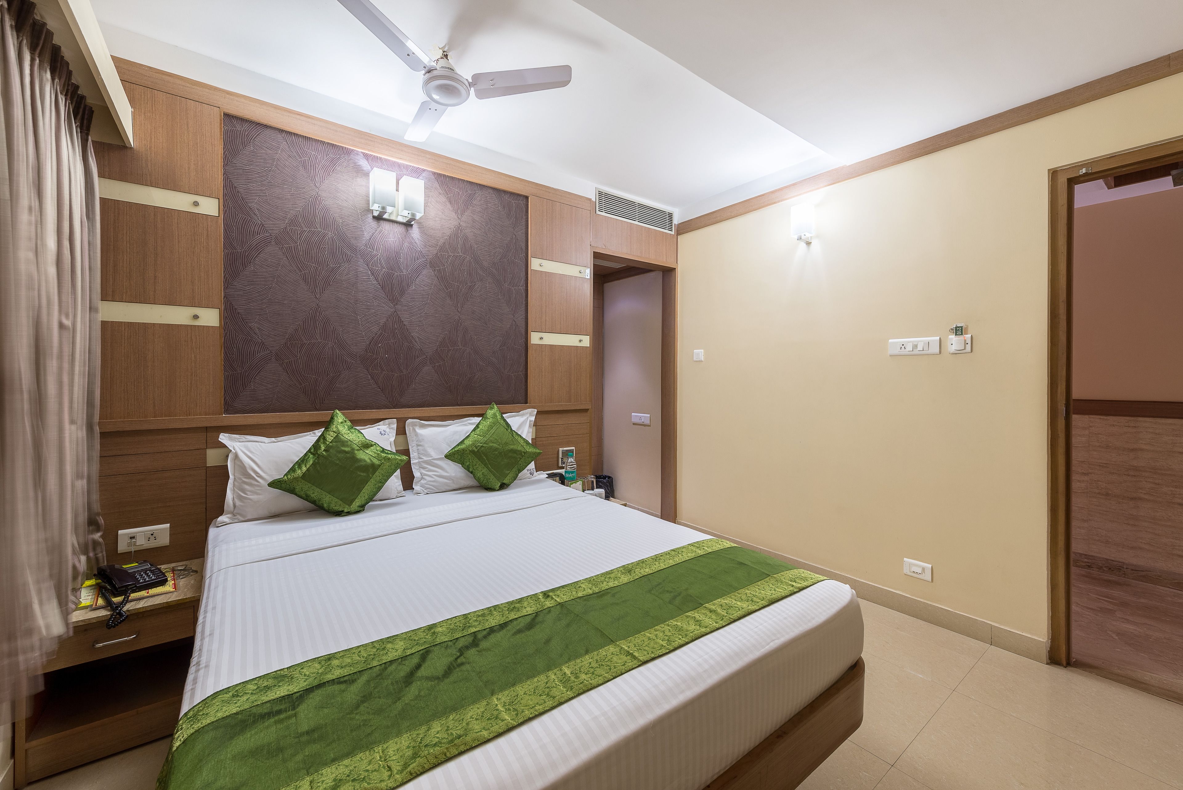 Ein Hotelzimmer mit Bett, Nachttisch, Deckenventilator und Tür.