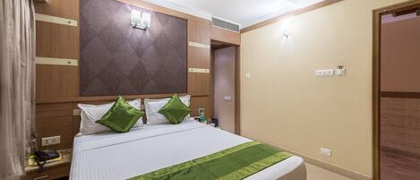 Una camera d'albergo con un letto, un comodino, una ventola a soffitto e una porta.