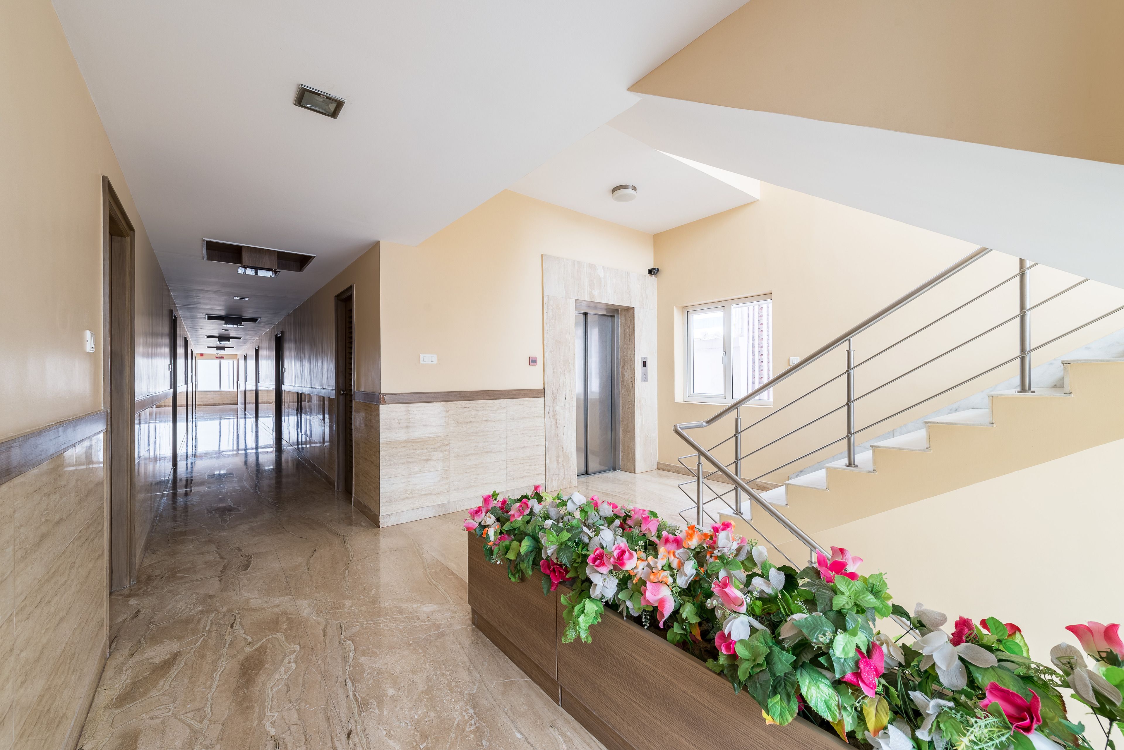 Un moderno vestíbulo de hotel con piso de mármol, un mostrador de recepción de madera y una escalera.