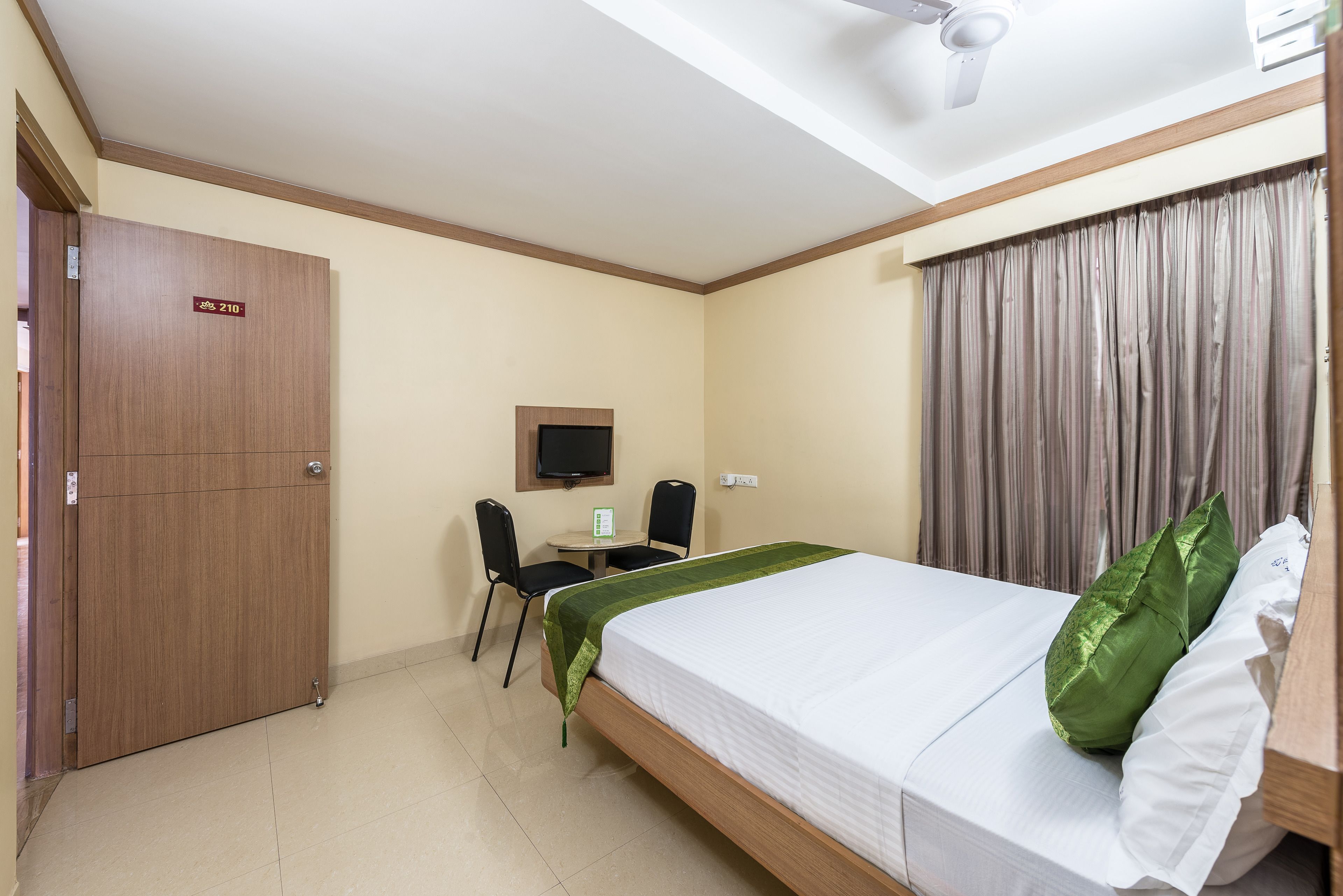 Habitación de hotel con cama, escritorio, silla, televisor y armario.