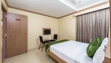 Habitación de hotel con cama, escritorio, silla, televisor y armario.