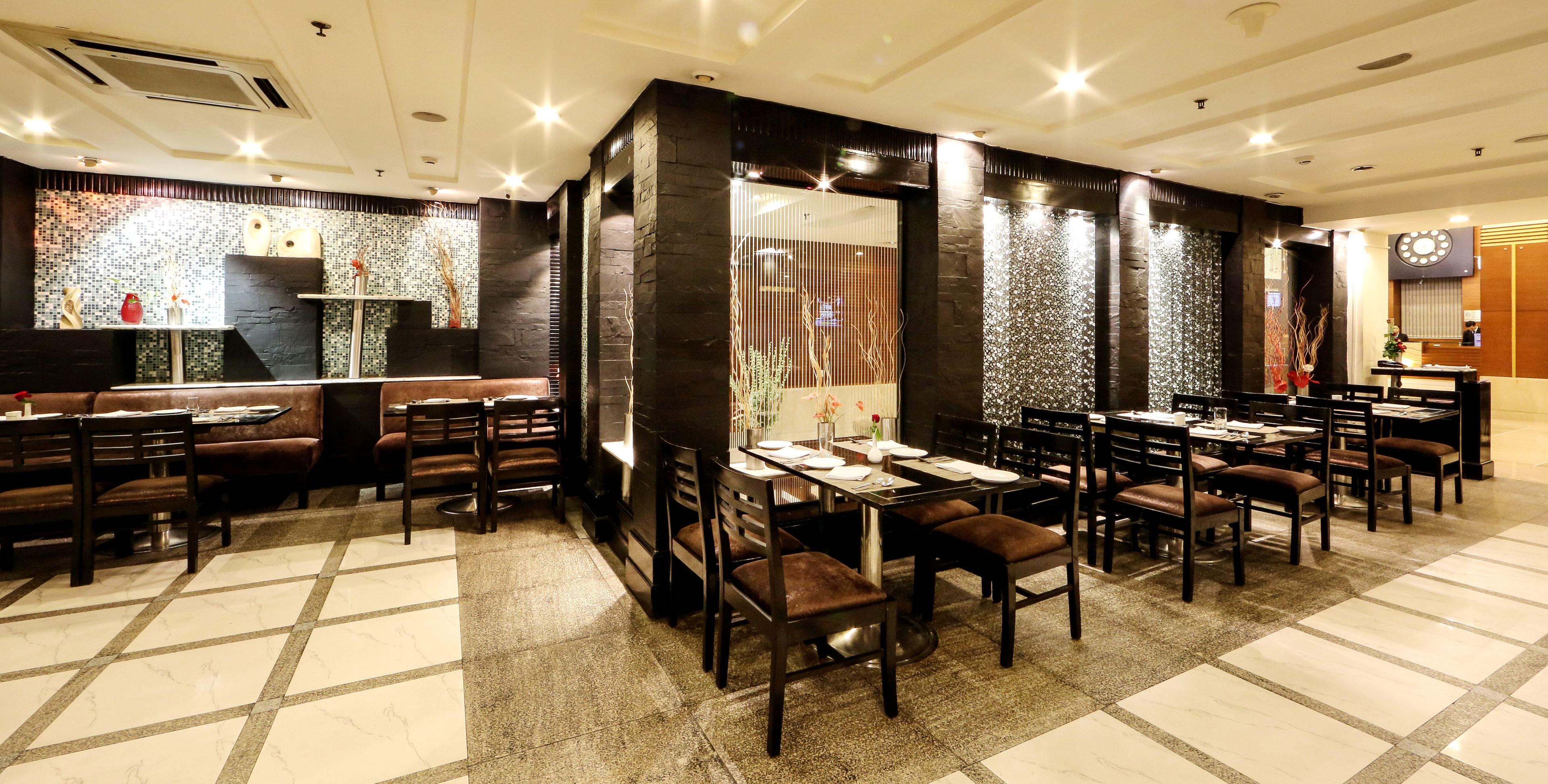 Um restaurante com cabines e mesas, paredes de pedra e chão de azulejos.