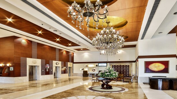 A spacious lobby with a grand chandelier, elevators, and a reception desk. - Regenta Central Klassik (Ludhiana)