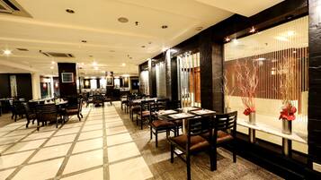 A spacious restaurant with high ceilings, multiple dining tables, and chairs.