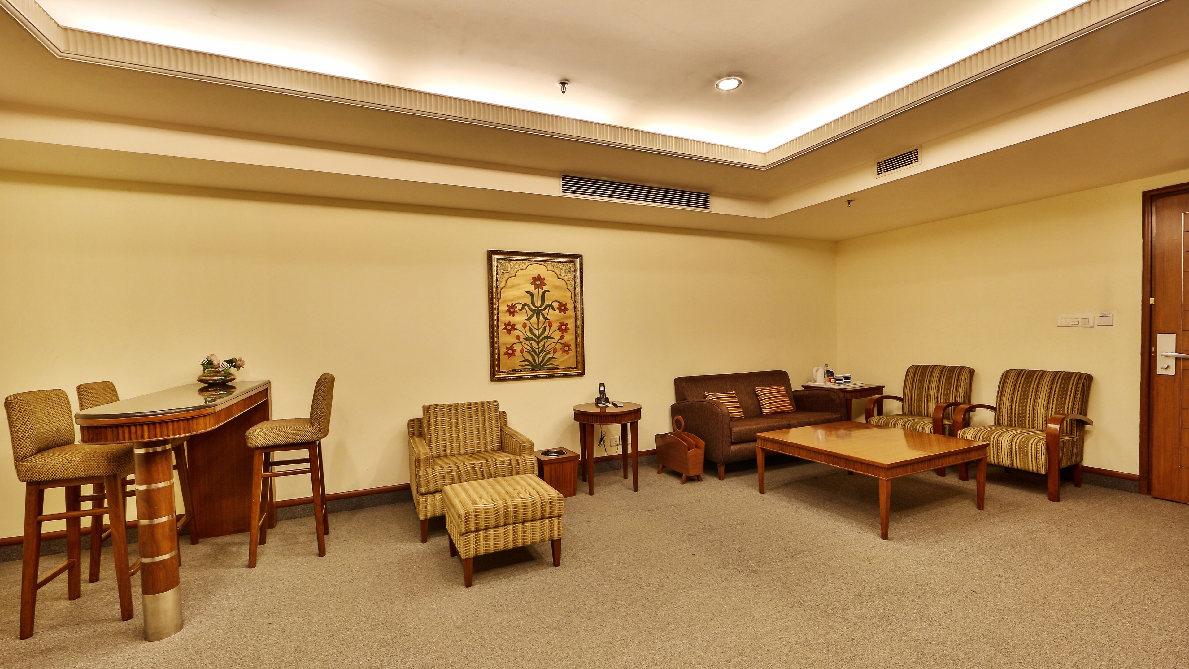 A conference room with a round table, chairs, a small side table, and a wall-mounted painting.