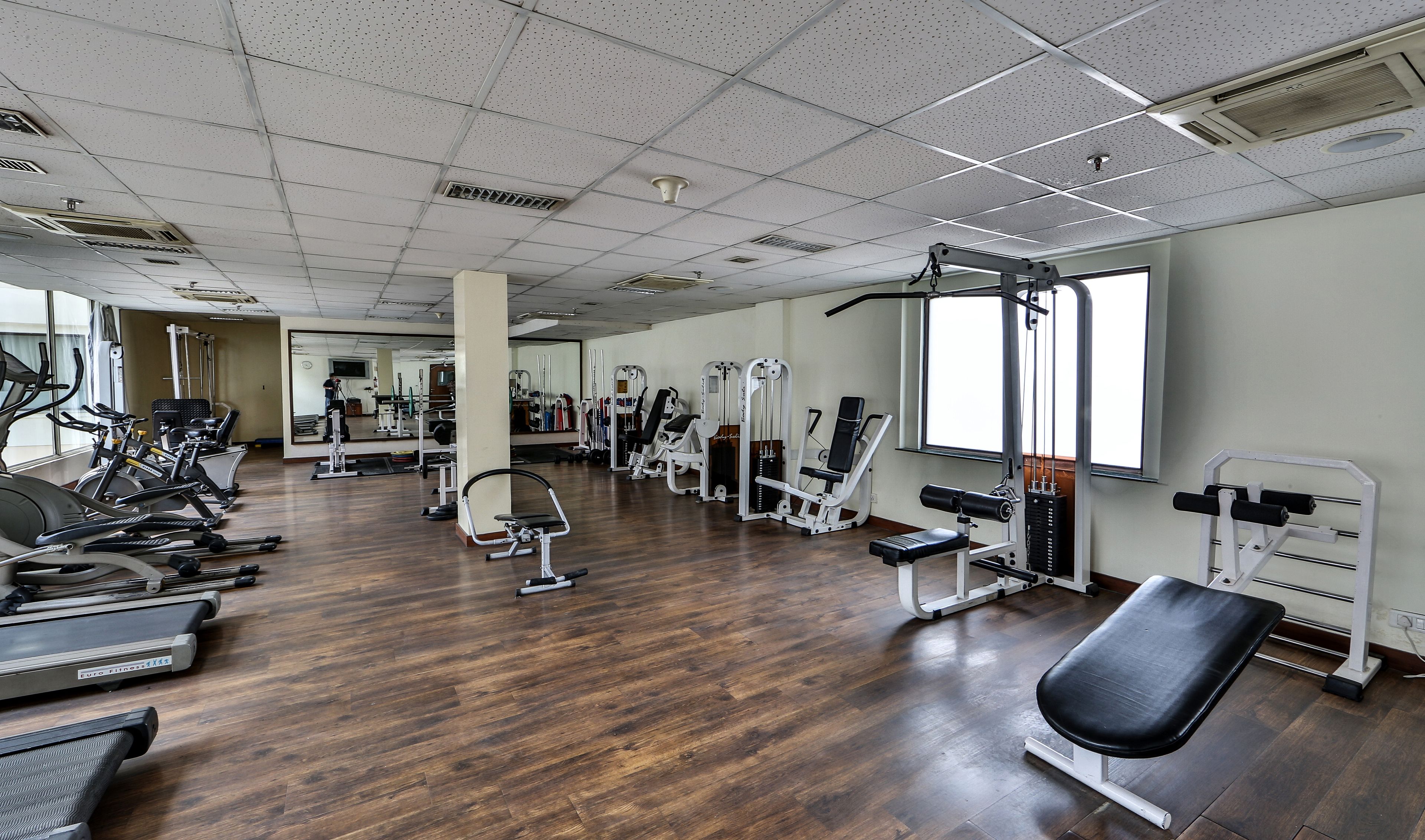 Ein Fitnessstudio mit Laufbändern, Krafttrainingsgeräten und Spiegeln.
