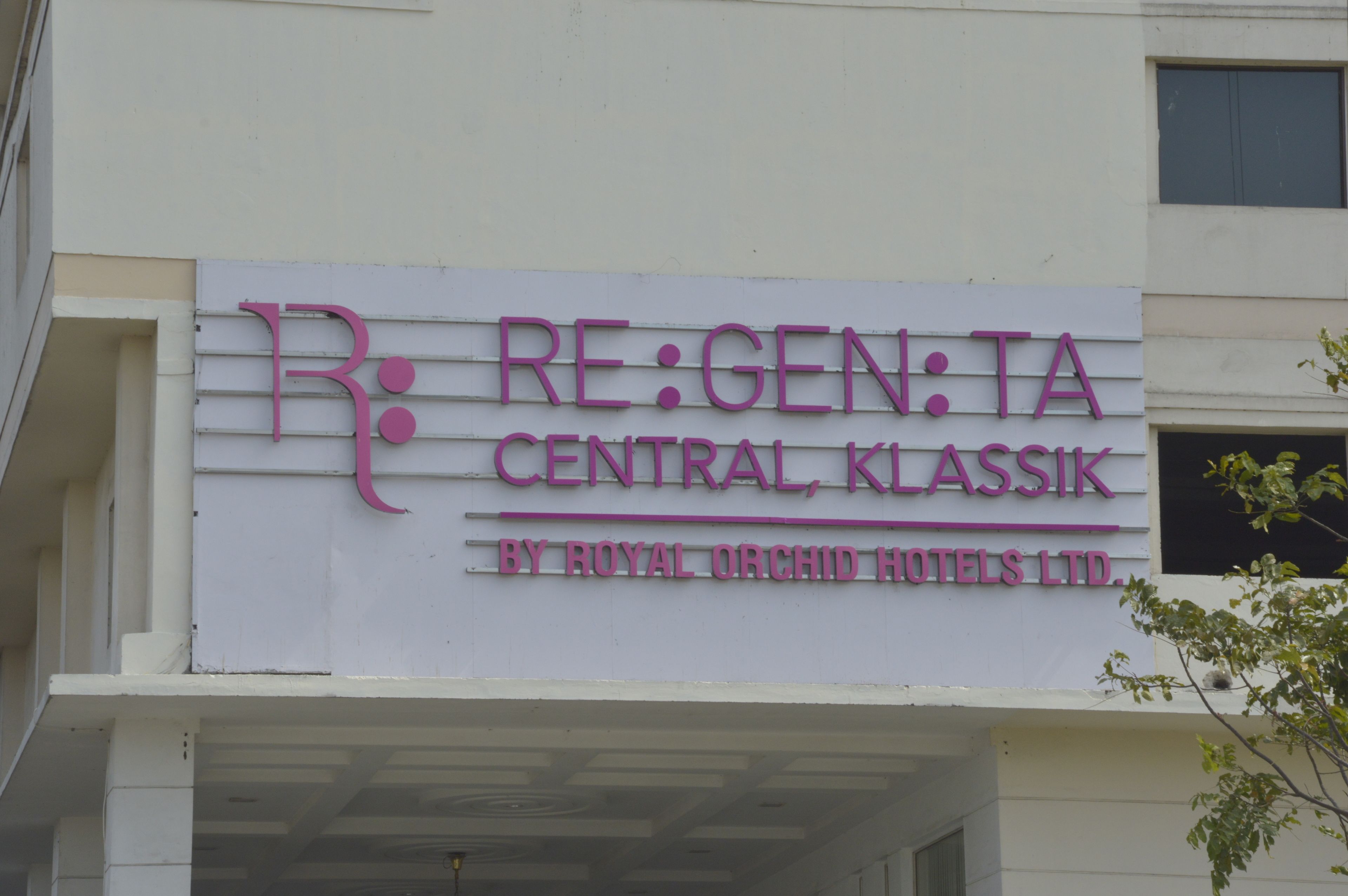 A hotel sign with the name "RE:GEN:TA CENTRAL, KLASIK" and "BY ROYAL ORCHID HOTELS LTD."