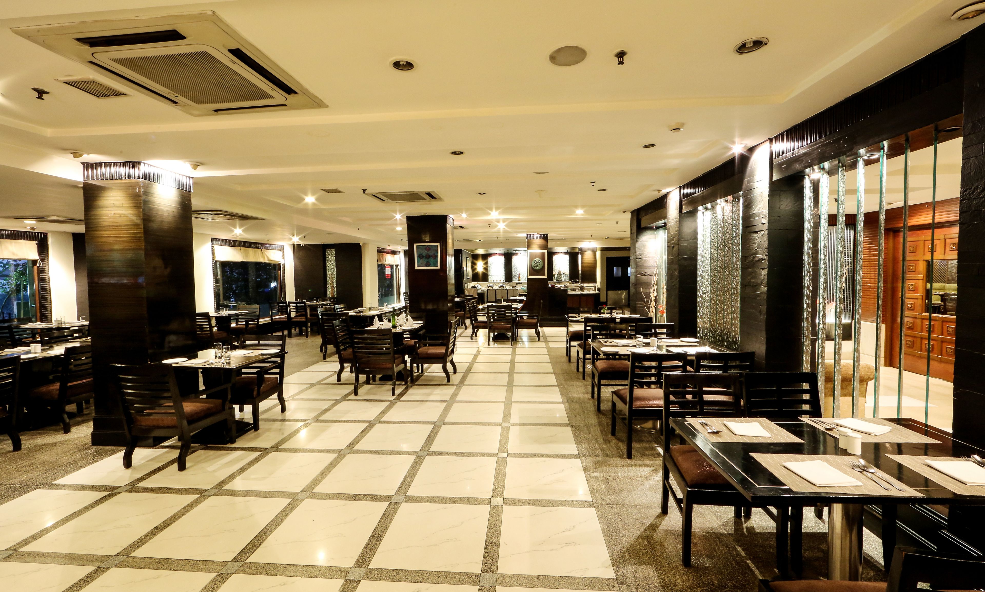 A spacious restaurant with a high ceiling, multiple dining tables, and chairs arranged in a central aisle.