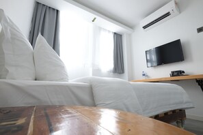 A hotel room with a bed, a wooden table, a TV, and a window with curtains. - White Loft Hotel (Malacca City)