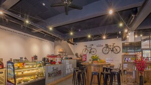 Un interior de cafetería con mostrador, zona de estar y una exhibición de bicicletas en la pared.