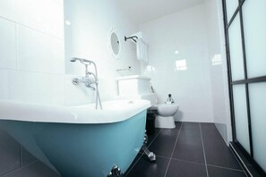A modern bathroom with a freestanding bathtub, a toilet, and a bidet. - White Loft Hotel (Malacca City)