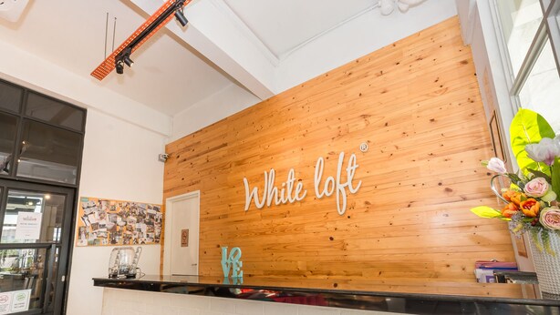 Una mesa de recepción con un panel de madera y el nombre "White loft" escrito en ella.
