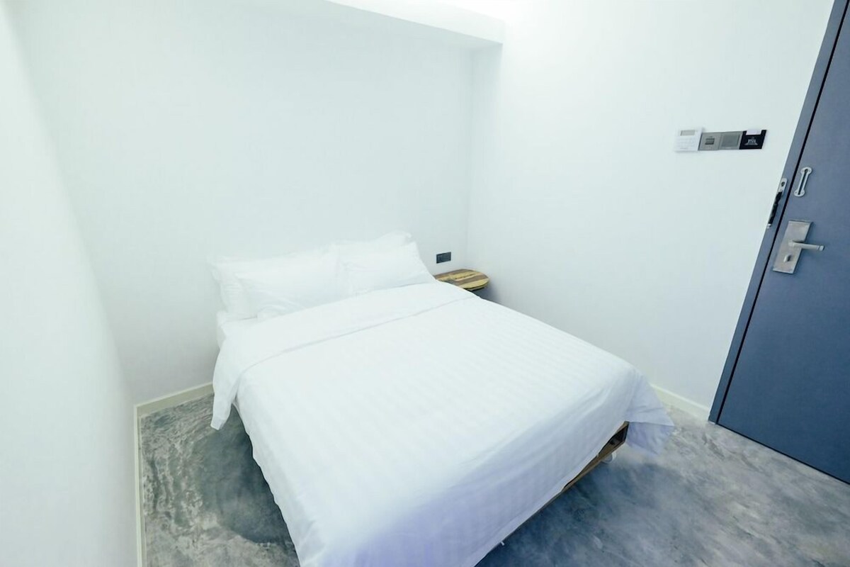 Una habitación pequeña con cama individual, cabecera de madera, mesita de noche y armario.