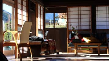 A traditional Japanese room with tatami flooring, a low wooden table, and a sofa with cushions.