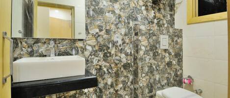 Un baño con lavamanos blanco, pared de mármol y retrete.