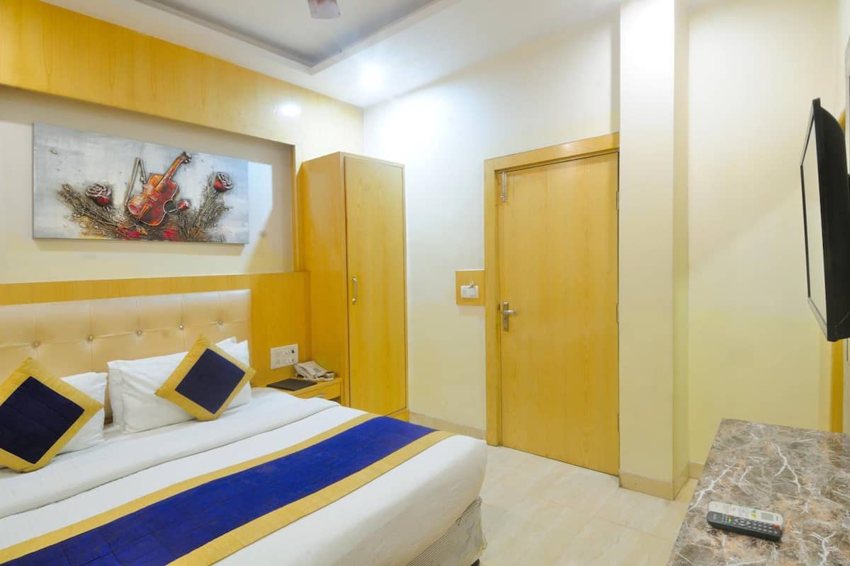 Una camera d'albergo con un letto, un armadio in legno, una televisione e un quadro appeso al muro.