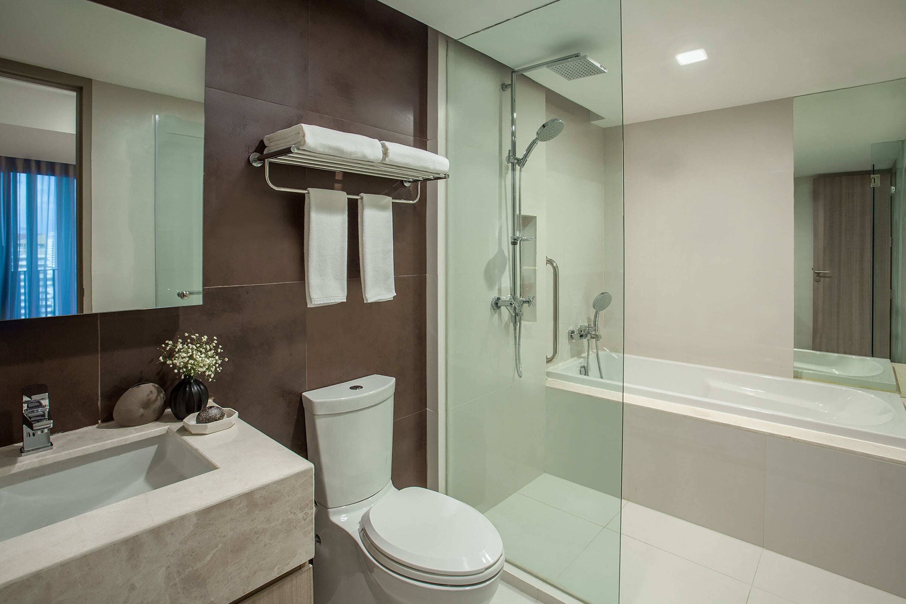 A modern bathroom with a glass-enclosed shower, a large bathtub, and a toilet.