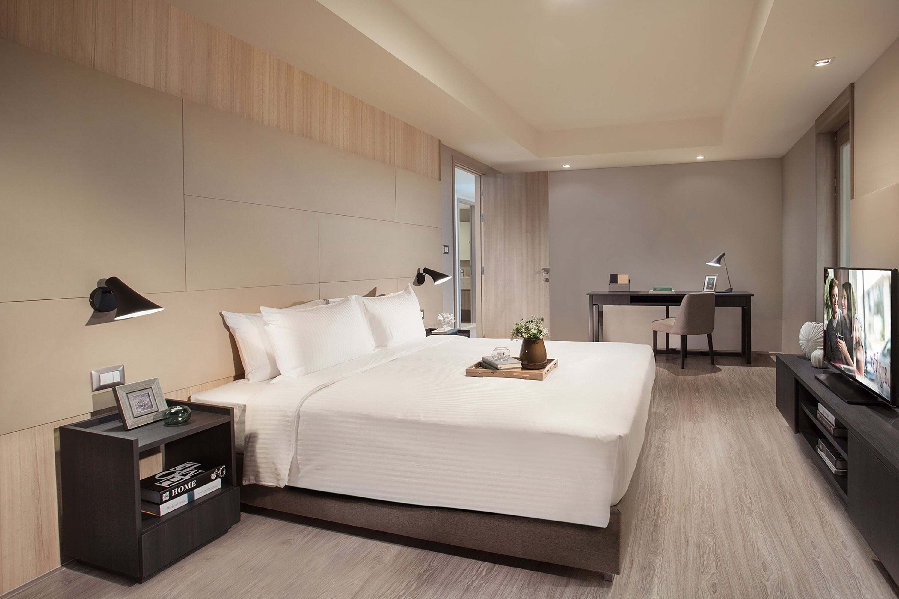 Una habitación de hotel moderna con una cama grande, un escritorio y una televisión.