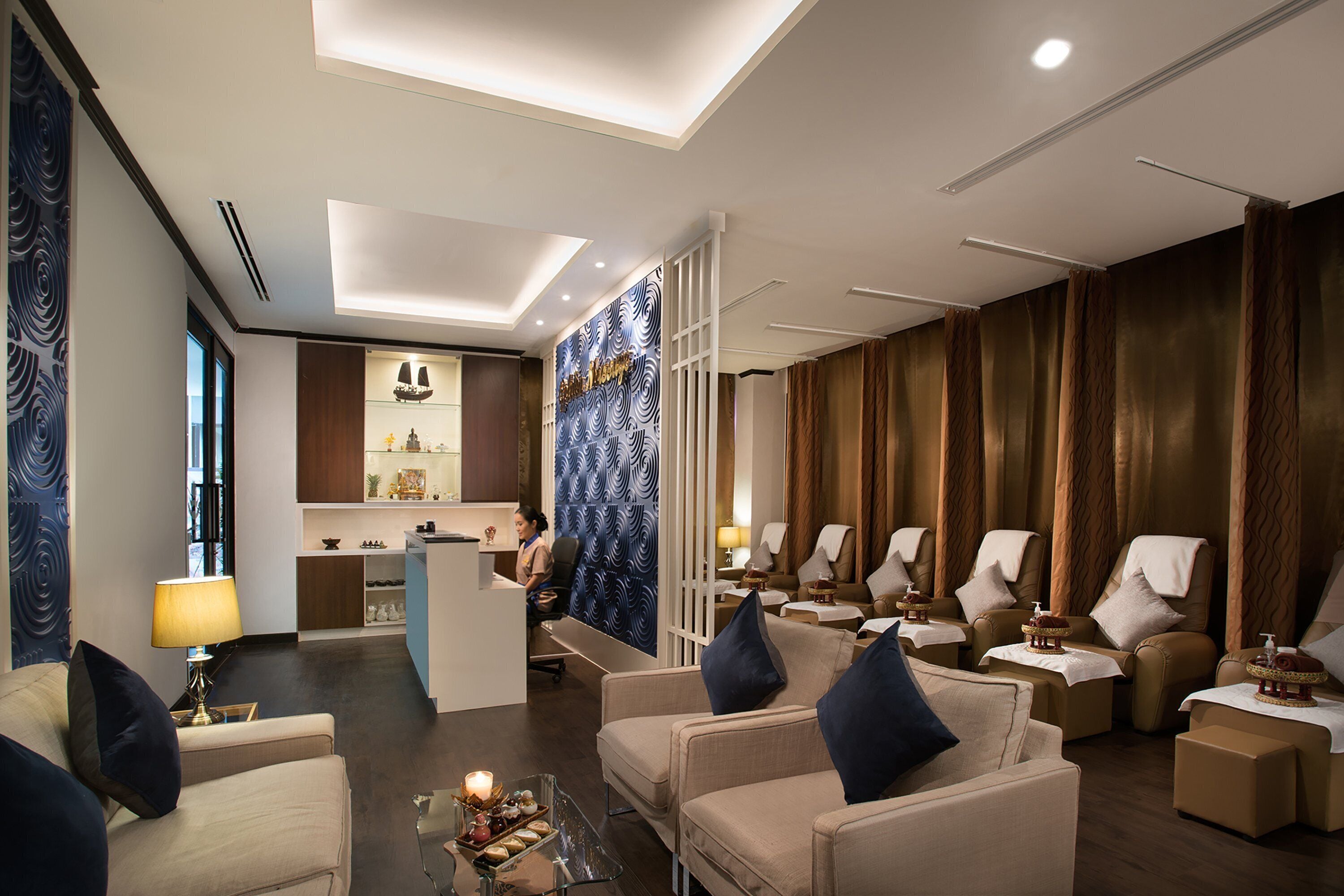 A modern hotel lobby with a reception desk, seating area, and a decorative wall.