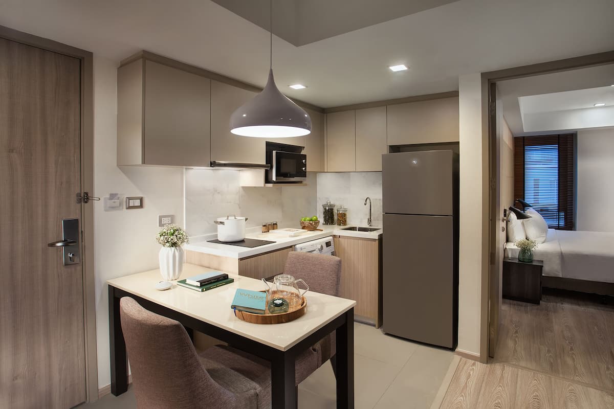 Una cocina moderna con comedor, un refrigerador y una cama en la habitación contigua.