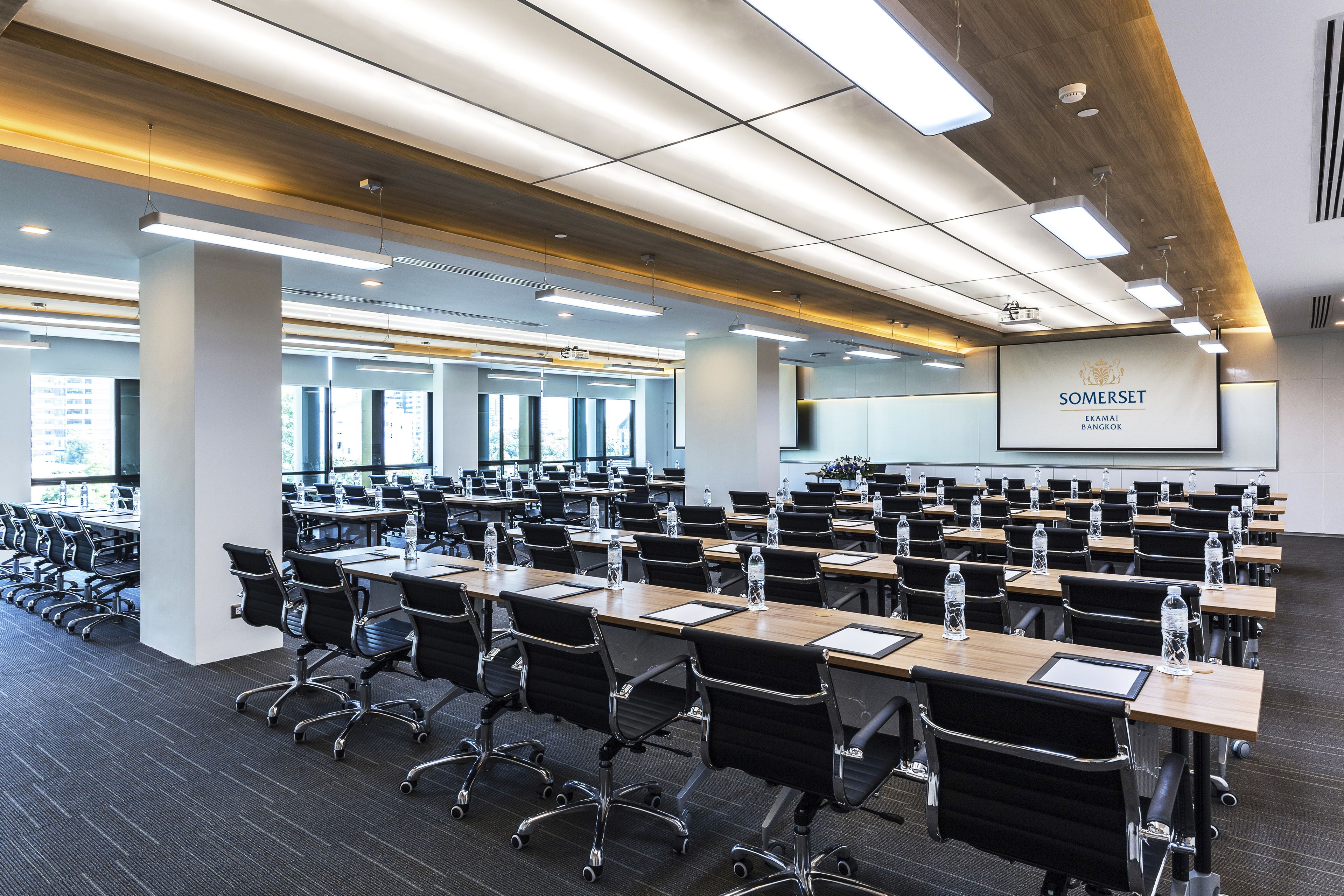 A conference room with rows of tables, chairs, and a presentation screen.