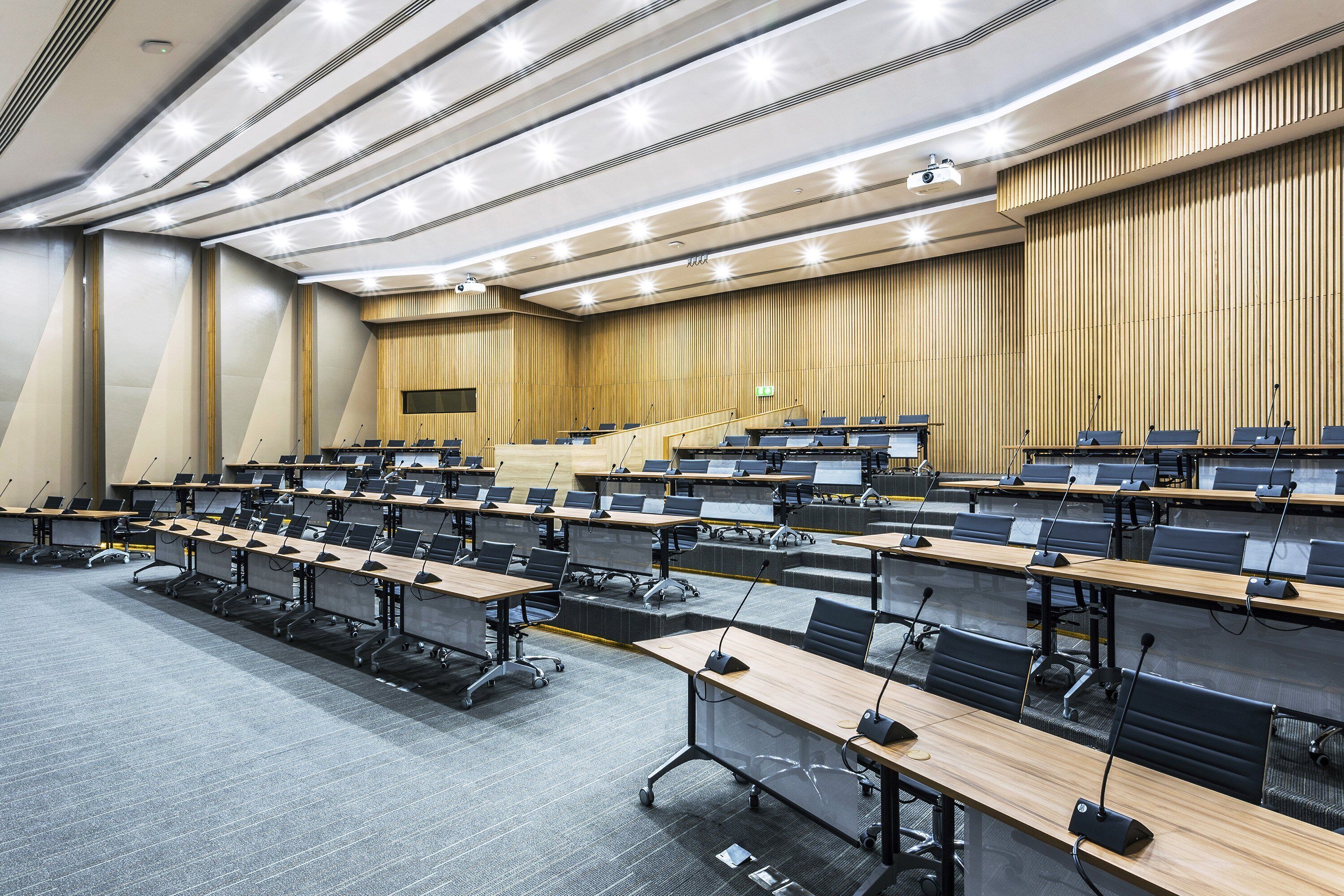 A conference room with multiple rows of tables, each equipped with a laptop and a microphone.